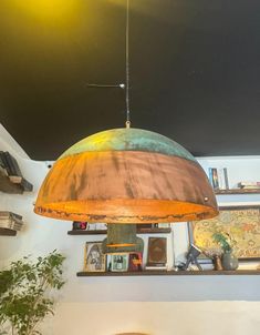 a lamp hanging from the ceiling in a room with pictures on the wall and shelves