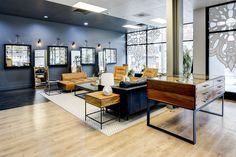 an office with wood flooring and furniture in front of large windows that look out onto the street