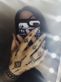 a woman taking a selfie with her cell phone in front of her face and tattoos on her hands