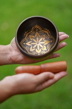 a person holding two carrots in their hand with a bowl on the other side