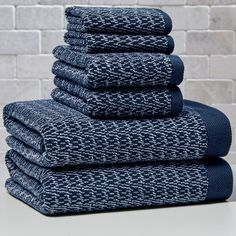 stack of folded towels in front of a brick wall with white and blue patterns on it