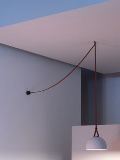 a lamp hanging from the ceiling next to a wall with a light bulb on it