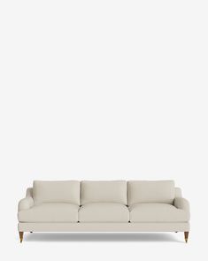 a white couch sitting on top of a wooden floor next to a wall with a light colored