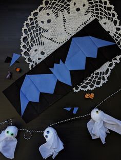 some paper bats are on a doily next to other crafting supplies and decorations