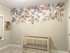 a baby's room with a crib and floral wallpaper on the walls