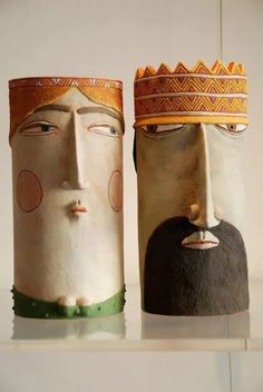 two vases with faces are sitting on a shelf