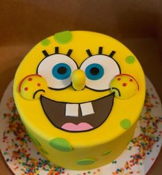 a yellow cake decorated with sprinkles and a smiley face on the top