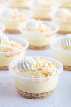 several desserts in small plastic containers with white frosting and toppings on top