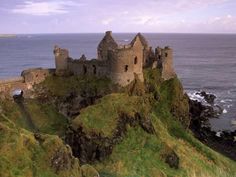 an old castle sitting on top of a cliff next to the ocean