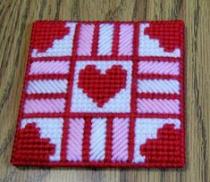 a red and white square with hearts is on a wooden table next to some scissors