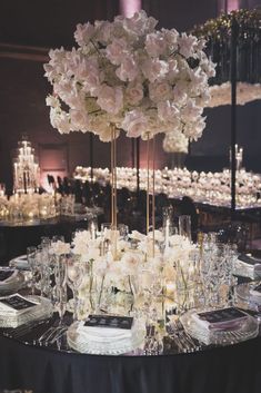 the centerpiece is surrounded by tall white flowers and candles in clear glass vases