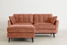 an orange couch and footstool on a white floor with a wall in the background