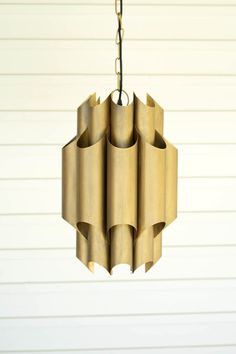 a light fixture hanging from the ceiling in front of a white wall with vertical lines