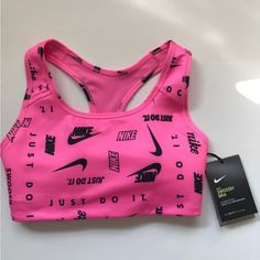 Brand New, Nike Swoosh Logo Printed Medium-Support Sports Bra In Size Xs. This Fun, Bright, Pink Sports Bra With Various Black Nike Logos/Slogans Has A Racerback Design And A Removable One-Piece Bra Pad. There’s A Bra Pad Pocket That Opens From The Top. It’s A Stretchy Fabric With Dri-Fit Technology That Helps Keep You Feeling Dry, Comfortable, And Supported. Never Been Worn, Comes New With Original Tags. Pink Activewear For Sports Events And Season, Pink Breathable Sports Bra, Pink Breathable Sports Bra For Sports Events, Pink Letter Print Activewear For Sports, Sporty Pink Activewear With Go-dry Technology, Pink Athleisure Activewear With Letter Print, Functional Pink Sports Bra For Sports Events, Pink Sports Bra For Sports Events, Pink Sporty Activewear For Light Sports