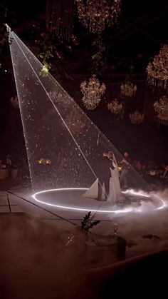 a man and woman dancing on a circular stage with lights in the air at night