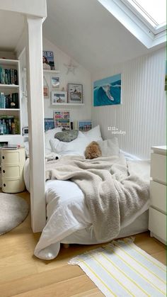 a bedroom with a white bed and lots of books on the shelves above it,