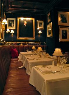 a dining room with white table cloths and pictures on the wall above it, along with red leather booths