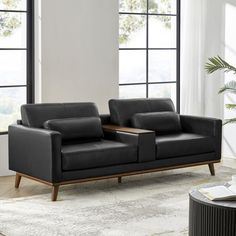 a living room with two black couches and a coffee table in front of large windows