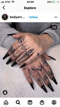 a woman's hand with black nails and tattoos on it