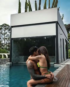 a man and woman sitting next to each other in front of a pool