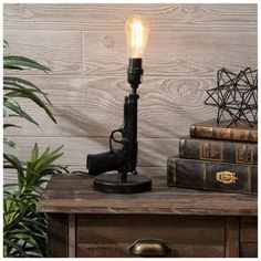 Base Dimensions: 6" x 5.38" Full Height: 12" Cord Length: 61.5" Bulb Type: A 60W Power Source: Corded Electric Material: Resin Color: Black Quantity: 1 Shoot straight for an action hero theme with our Black Pistol Decorative Table Lamp! This cool lamp offers a realistic upright pistol shape with a brushed black finish and distressed gold details. Add a light bulb and a lampshade to shed some light in your bedroom, man cave, or shop! Cool Lamp, Electric Material, Upcycled Lighting, Bedroom Man Cave, Action Hero, Large Lamps, Room Stuff, White Lamp Shade, Cool Lamps