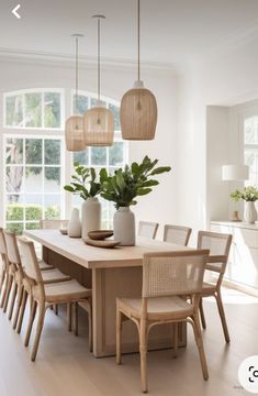 a dining room table and chairs with plants in vases on the top one side