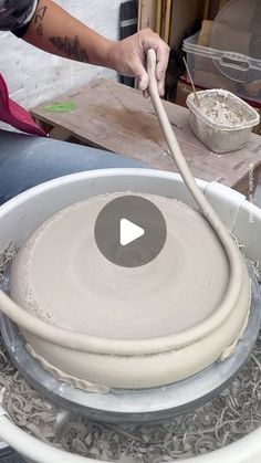 a person is making something out of clay in a bowl with a hose attached to it