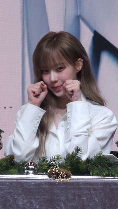 a young woman sitting at a table with her hands on her face