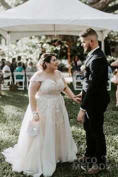 a bride and groom holding hands under a tent