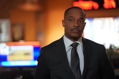 a man wearing a suit and tie in front of a tv screen with neon signs