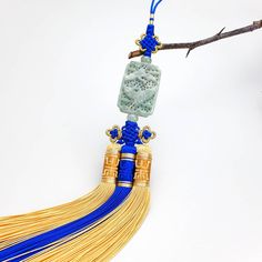 a tassel hanging from a twig on a tree branch with blue and gold beads