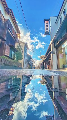 an empty street with buildings and clouds reflected in the water