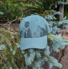 This wood burned green faux suede baseball cap would make a great addition to any nature lover's wardrobe. I hand burnt a mountain range around the entire crown of the hat with pine trees growing along it using a pyrography tool and a freehanded original design. Then, for a unique finishing touch I burnt a full moon with craters and stars in the sky above the landscape. Materials: 100% cotton Hat fits most with an adjustable buckle in the back *Disclaimer* colors may vary slightly from screen to screen Moon Hat, Pyrography Tools, Outdoorsy Gifts, Celestial Gifts, Hand Burn, Hat Fits, Dad Cap, Landscape Materials, Cotton Hat