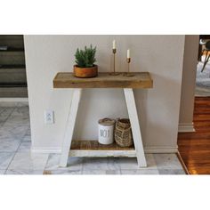 a small wooden table with two candles on it and a potted plant next to it