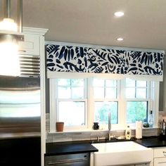 a kitchen with black counter tops and white cupboards next to a window covered in blue leaves