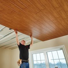 a man is working on the ceiling in his new home with wood planks installed