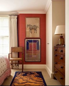 a bedroom with red walls and pictures on the wall