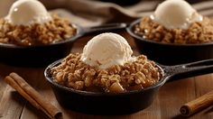 three skillets filled with ice cream and granola on top of a wooden table