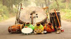 an assortment of musical instruments sitting on the side of a road in front of trees