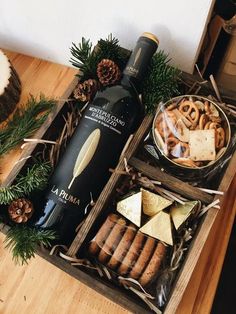 a bottle of wine, cheese and crackers in a wooden box on a table