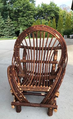 a chair made out of wood sitting on the ground in front of some green trees