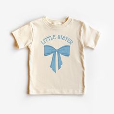 This cute toddler Coquette little sister shirt is 100% cotton, has a tear away tag for your toddler's comfort and comes in 3 Bella Canvas colors. In sizes 2T-5T, choose Black, White or Natural to make this Little Sister Bow announcement shirt the sweetest sister shirt! Don't see your size? Message me! I love custom orders. DETAILS .100% Cotton .Bella Canvas tee .Tear away label .Runs true to size .Props in any photos are not included and are for styling purposes only .Colors may slightly vary from styled photos  SIZING This graphic tee design will be printed on a Bella Canvas shirt that is high quality, comfortable and so soft! Sizing runs true to size (please refer to the size chart for exact measurements). If you'd like a more oversized look I would recommend ordering a size up. If you p Cute Cotton T-shirt With Name Print, Cute Blue Shirt As A Gift, Cute Cotton Tops For Birthday, Cute Blue Shirt For Gift, Cute Blue Shirt As Gift, Unisex Cotton Birthday Shirt, Cute Cotton Shirt For Gender Reveal, Cute Cotton T-shirt For Birthday, Cute Blue T-shirt For Gift