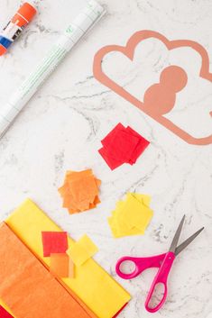 cut out paper and scissors on a marble table with crafting supplies next to it