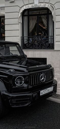 a black mercedes benz is parked in front of a building