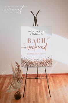 a welcome sign sitting on top of a wooden floor next to a vase with flowers