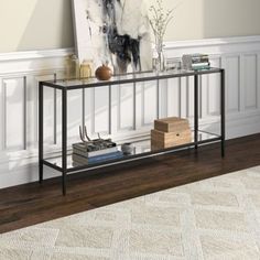 a black metal console table with books and magazines on it in front of a white wall