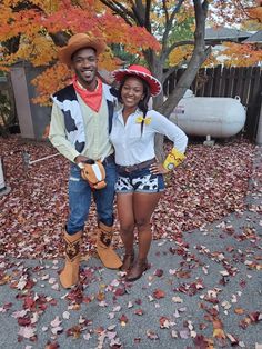 a man and woman are dressed up as toy story characters in the fall leaves outside