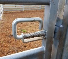 a metal gate with a bolt in the center and a paddock to keep horses out