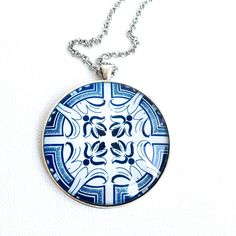 a blue and white pendant with an intricate design on it's chain hanging from a silver ball chain