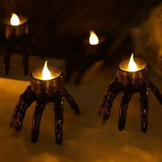 two hand - shaped candles are lit in the dark